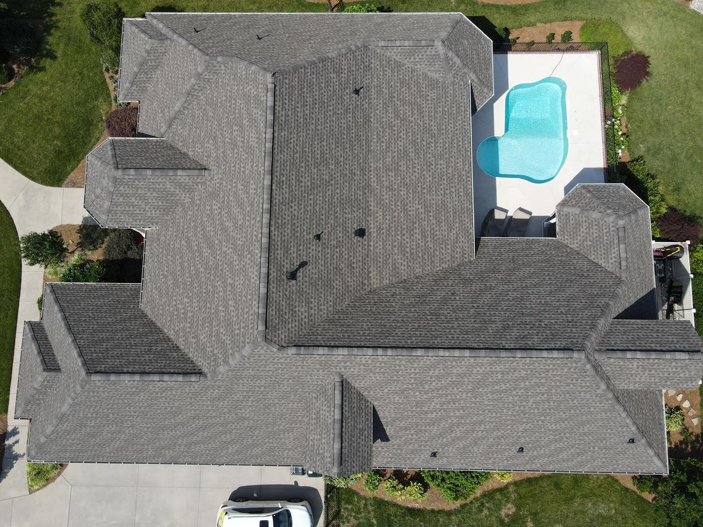 Aerial view of a large gray-roofed house with a backyard swimming pool