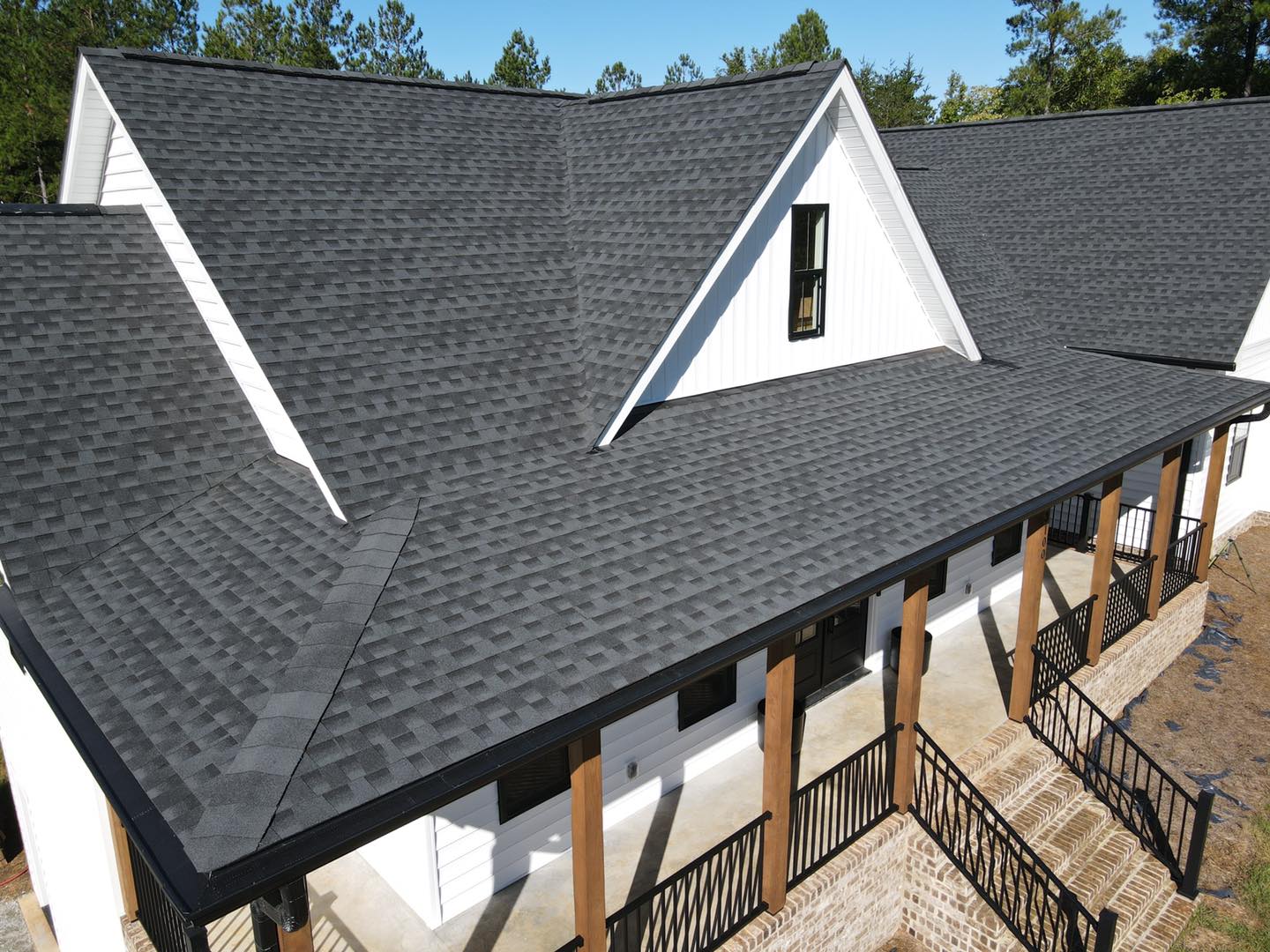 Angled view of a house with gray shingle roof, dormers, and porch columns