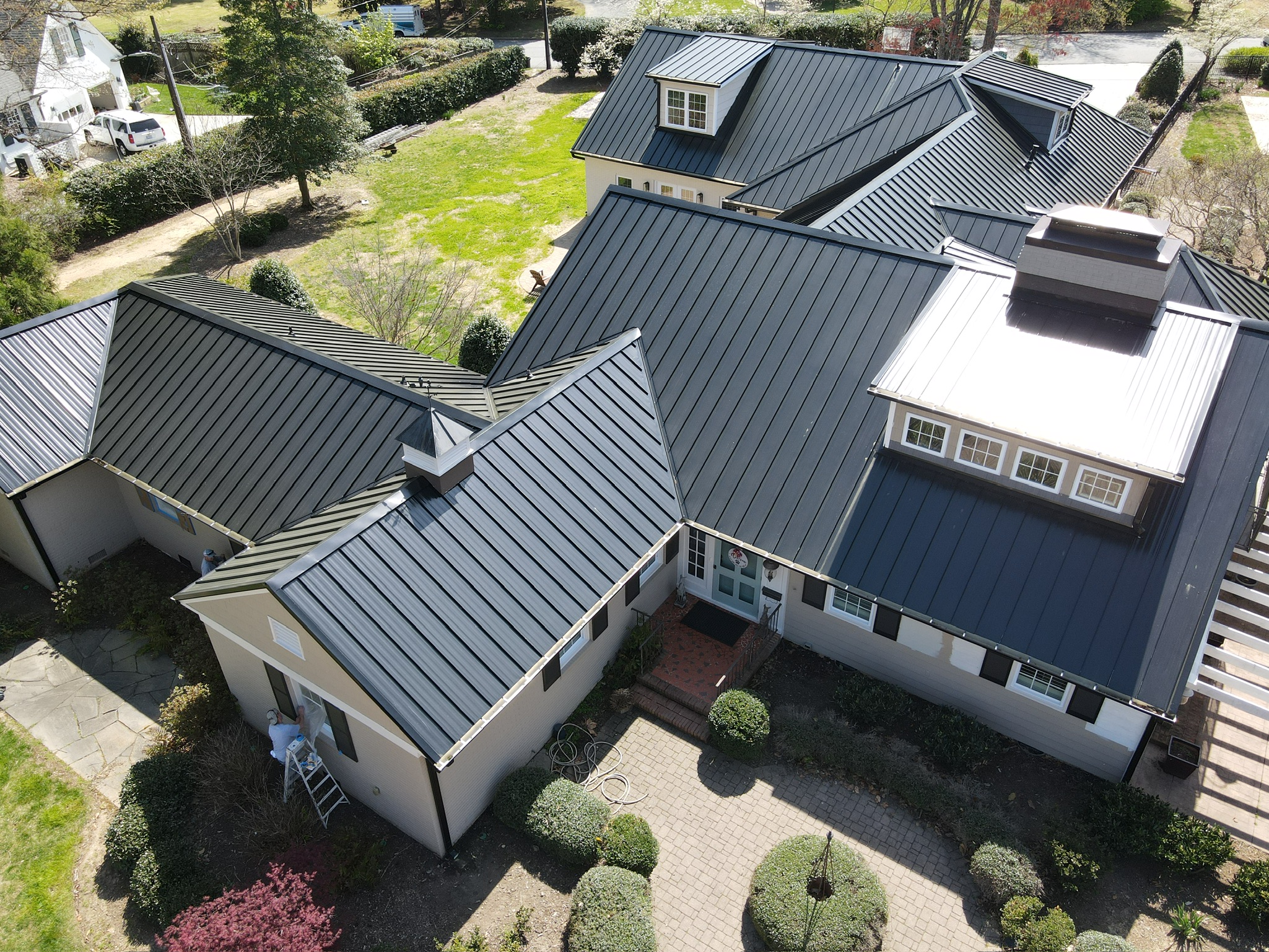 Aerial photo of a large house with dark metal roofs and landscaped gardens