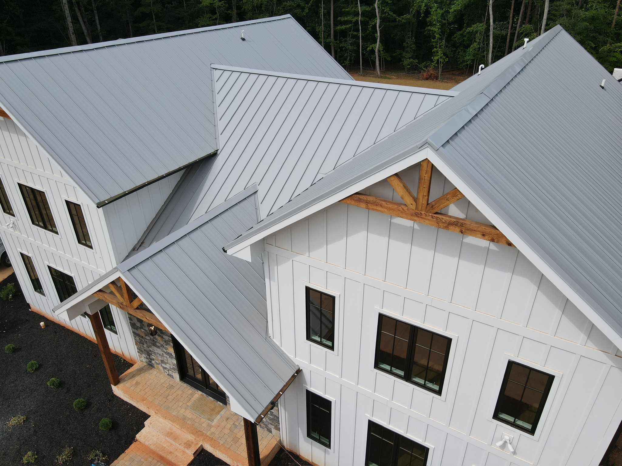 Aerial view of a large white house with gray metal roofs and wood accents.